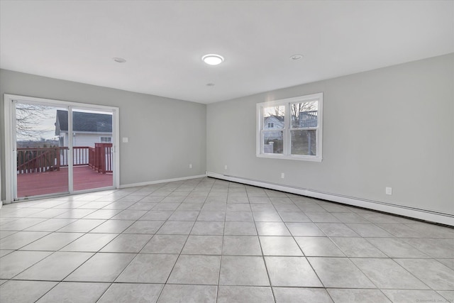 empty room with a baseboard heating unit, light tile patterned floors, and plenty of natural light