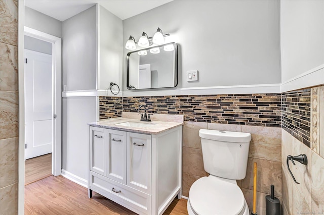 bathroom featuring vanity, toilet, hardwood / wood-style floors, and tile walls