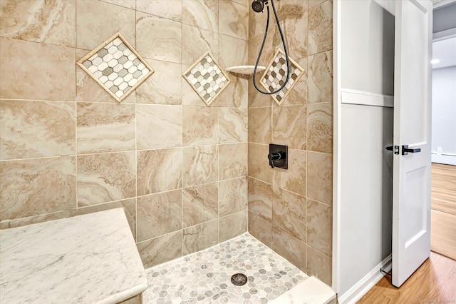 bathroom with a tile shower and hardwood / wood-style flooring