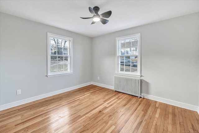 empty room featuring ceiling fan, radiator, and light hardwood / wood-style floors