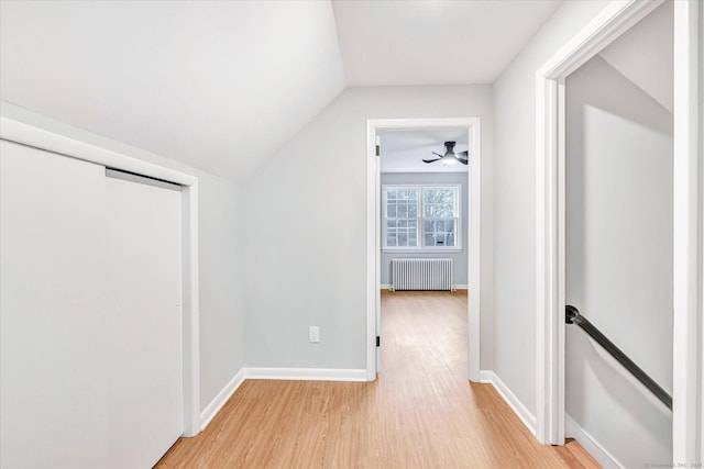 hallway featuring radiator heating unit, vaulted ceiling, and light hardwood / wood-style flooring