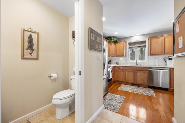 kitchen with stainless steel appliances, sink, light tile patterned floors, and backsplash