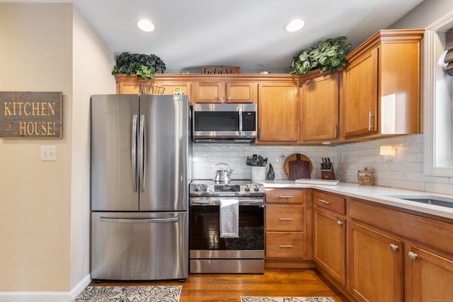 kitchen featuring stainless steel appliances, backsplash, and light wood-type flooring