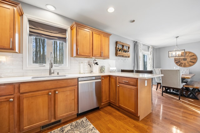 kitchen with sink, hardwood / wood-style flooring, dishwasher, hanging light fixtures, and kitchen peninsula