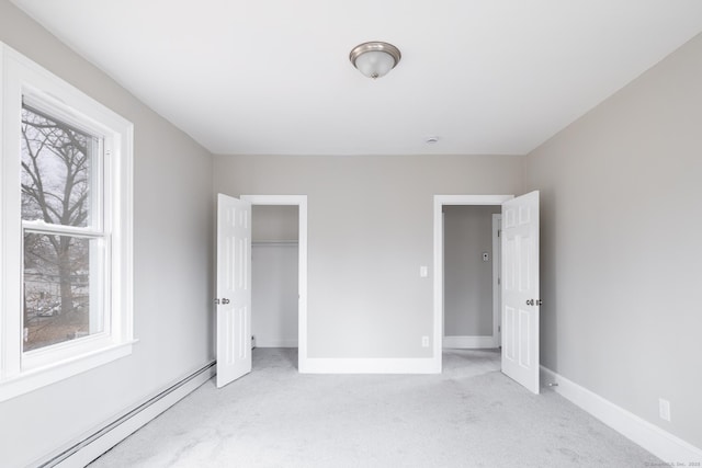 unfurnished bedroom featuring a baseboard radiator, light colored carpet, and a closet