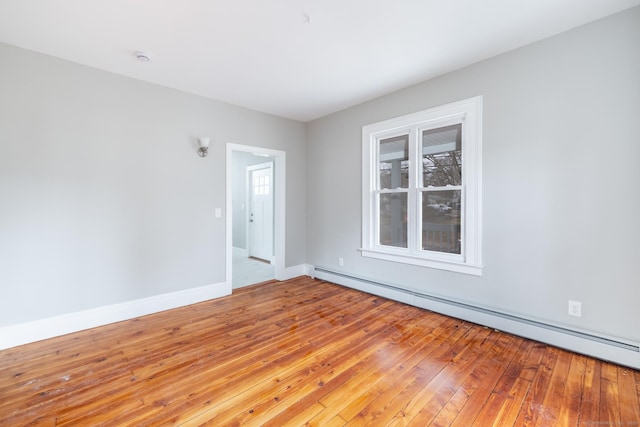 empty room with a baseboard radiator, light hardwood / wood-style flooring, and a wealth of natural light