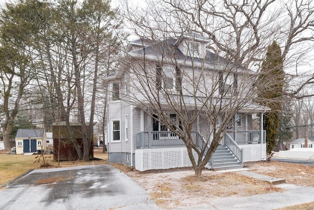 view of front of home with a porch and a shed