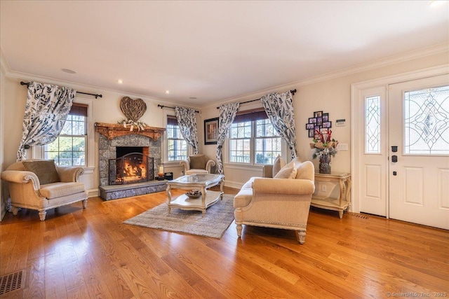 living room featuring a fireplace, ornamental molding, and light wood-type flooring