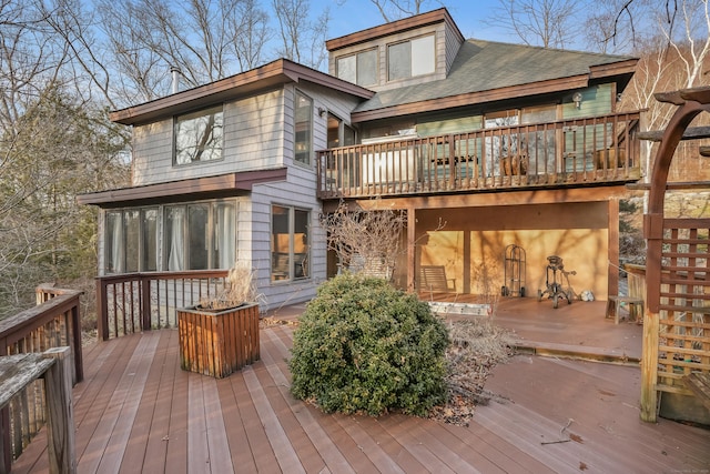 rear view of house with roof with shingles and a deck