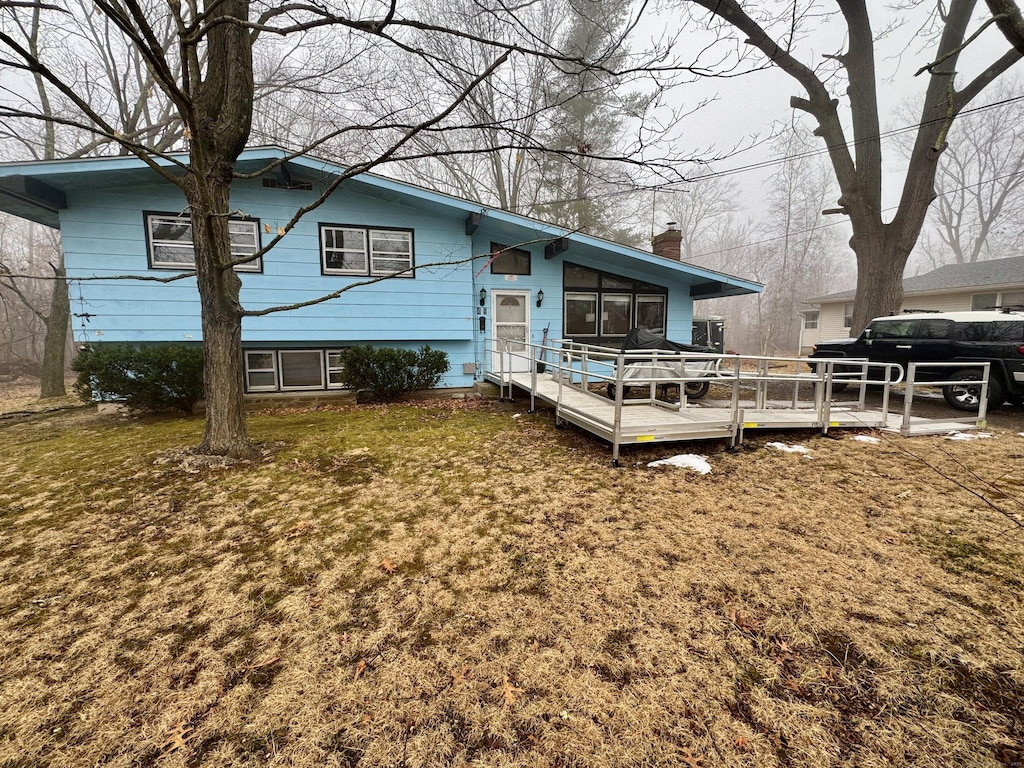 rear view of house with a wooden deck and a lawn