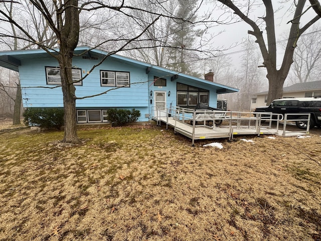 rear view of house with a wooden deck and a lawn