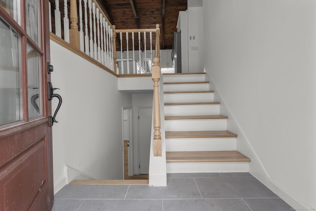 stairway with tile patterned floors and a high ceiling