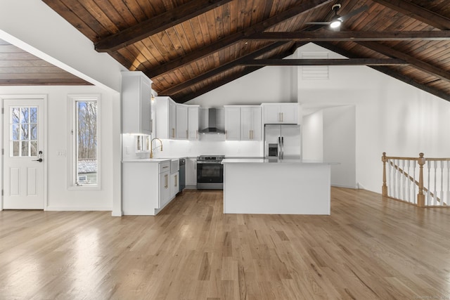 kitchen featuring wall chimney range hood, white cabinetry, stainless steel appliances, a center island, and light wood-type flooring