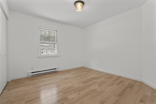 spare room featuring light wood-type flooring and a baseboard heating unit