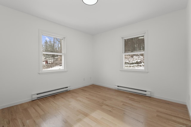 unfurnished room featuring a baseboard radiator and light wood-type flooring