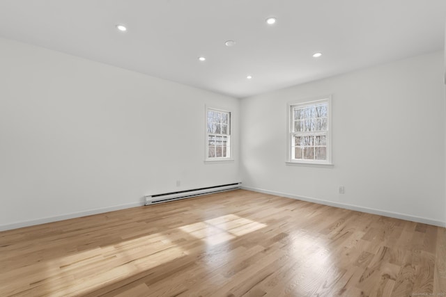 unfurnished room featuring a baseboard radiator and light hardwood / wood-style flooring