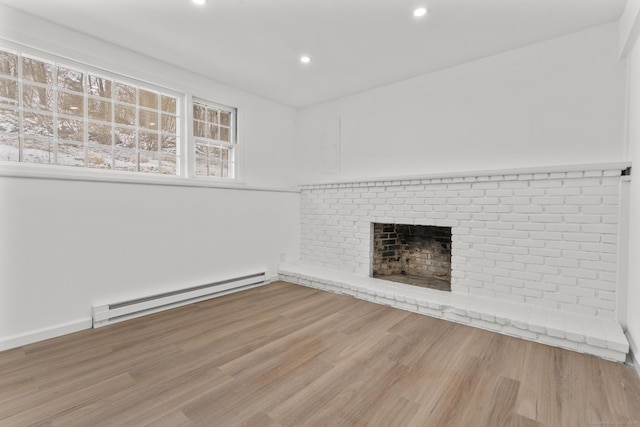 unfurnished living room with hardwood / wood-style floors, a fireplace, and baseboard heating