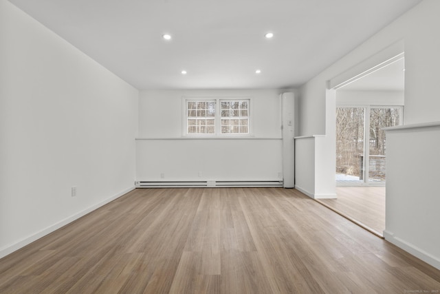 empty room with a baseboard heating unit and light hardwood / wood-style flooring