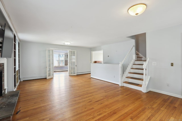 15 Seeley St, Danbury, CT 06810 - unfurnished living room featuring stairs, light wood-style floors, a brick fireplace, and a baseboard heating unit