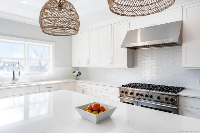 kitchen with backsplash, sink, range with two ovens, and white cabinets