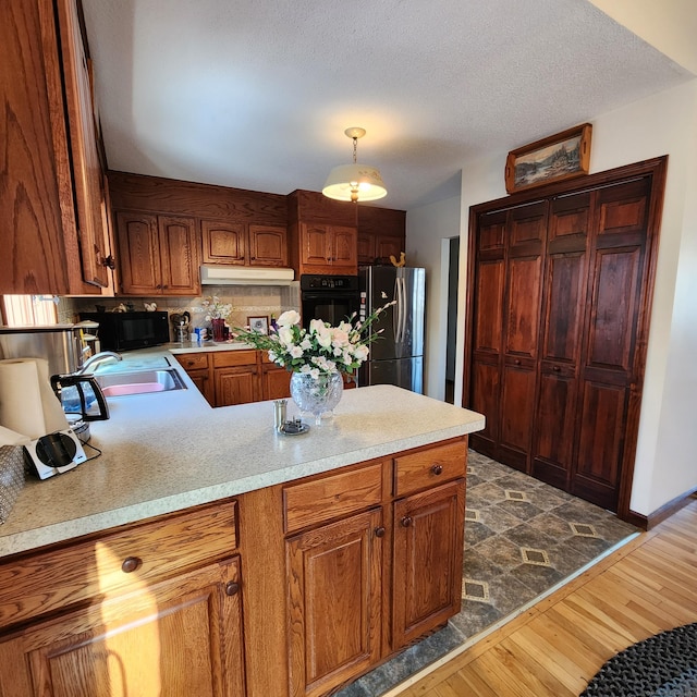 kitchen featuring dark wood-type flooring, sink, a textured ceiling, hanging light fixtures, and black appliances