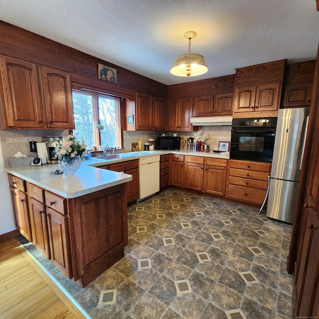 kitchen with tasteful backsplash, decorative light fixtures, sink, and black appliances