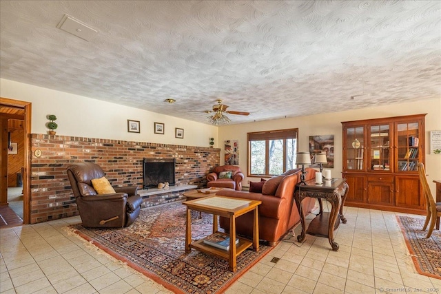 living room with ceiling fan, a brick fireplace, and a textured ceiling