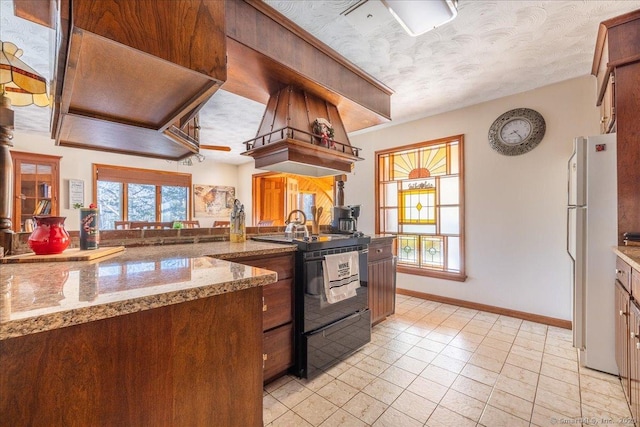 kitchen with light stone counters, black range with electric stovetop, a textured ceiling, and white fridge