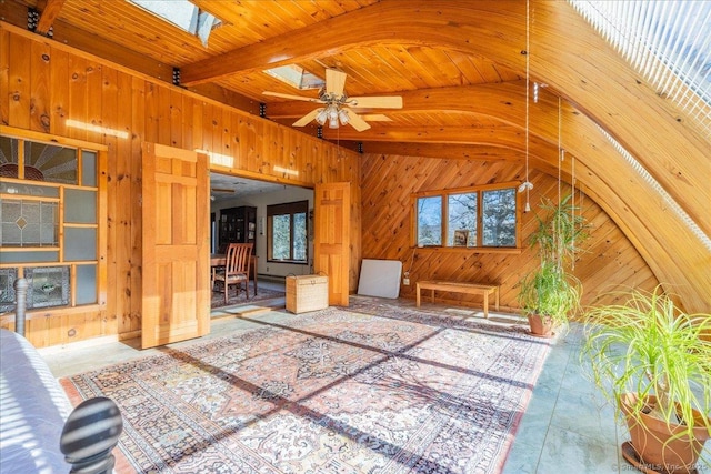 unfurnished living room with ceiling fan, a healthy amount of sunlight, and wooden walls