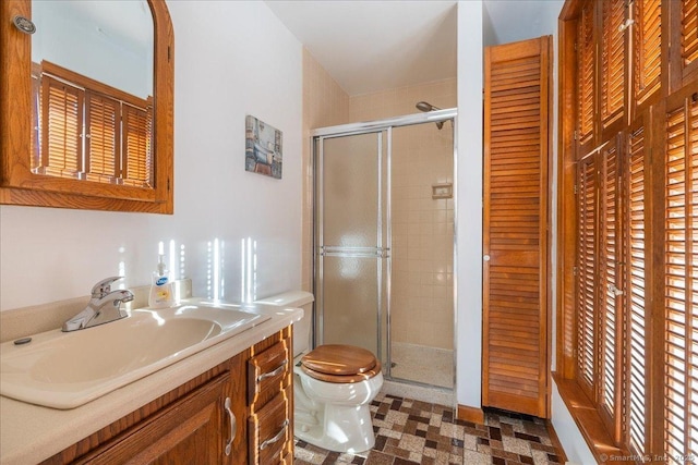 bathroom with vanity, toilet, and a shower with door