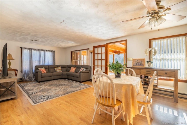 dining area featuring ceiling fan, a baseboard radiator, a textured ceiling, and light hardwood / wood-style flooring