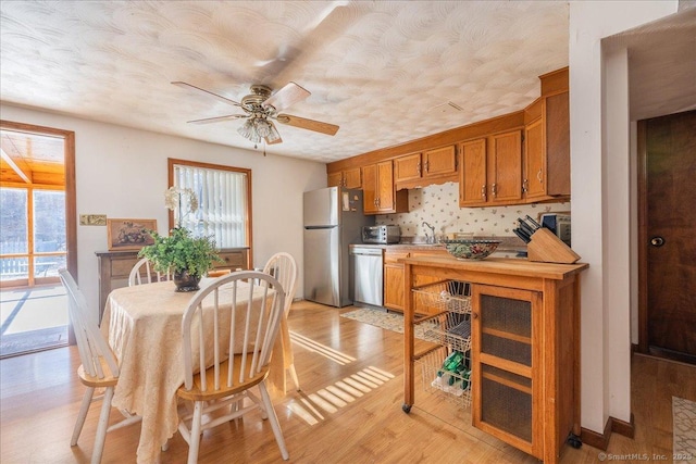 kitchen with decorative backsplash, ceiling fan, stainless steel appliances, a textured ceiling, and light hardwood / wood-style flooring