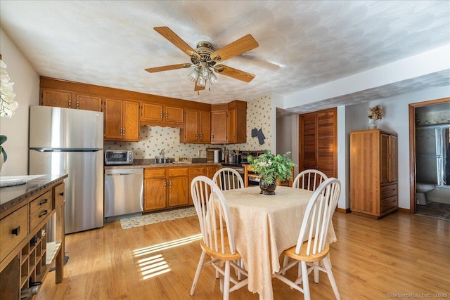 kitchen featuring sink, stainless steel appliances, light hardwood / wood-style floors, and ceiling fan