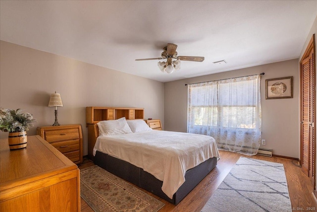 bedroom featuring ceiling fan, dark hardwood / wood-style floors, and a baseboard heating unit