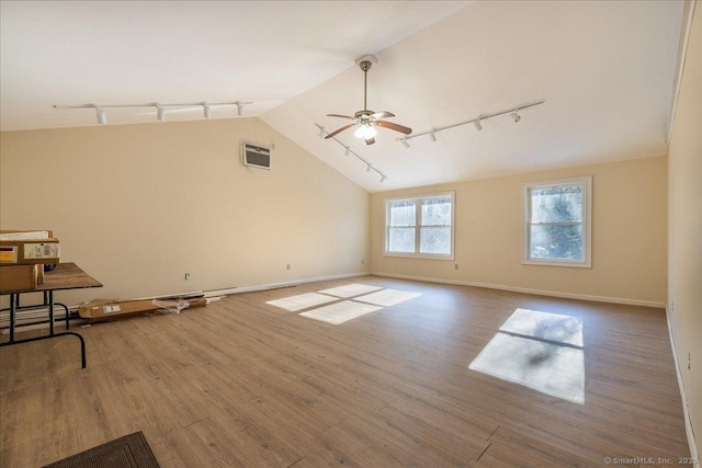 unfurnished living room with vaulted ceiling, hardwood / wood-style floors, rail lighting, ceiling fan, and a wall unit AC