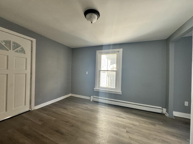 unfurnished room featuring dark wood-type flooring and a baseboard radiator