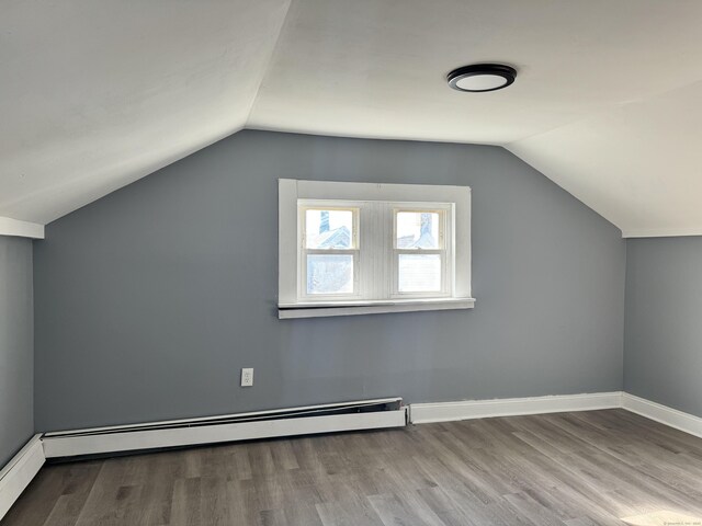 bonus room with lofted ceiling, a baseboard heating unit, and light hardwood / wood-style flooring