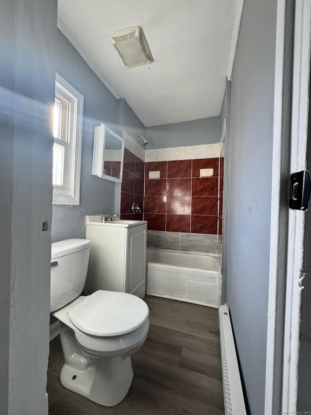 full bathroom featuring tiled shower / bath, a baseboard radiator, hardwood / wood-style flooring, vanity, and toilet