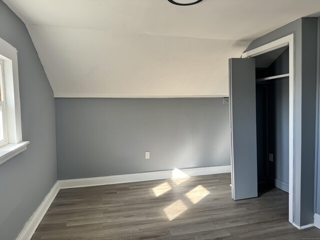 unfurnished bedroom with dark hardwood / wood-style flooring and lofted ceiling