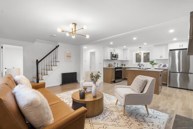 living room featuring light wood-type flooring, radiator heating unit, and a notable chandelier