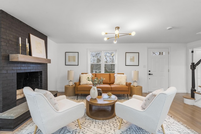 living room with a fireplace, light wood-type flooring, and a chandelier