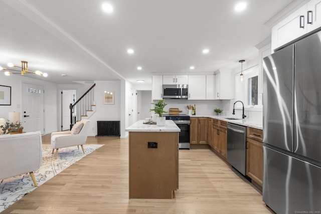 kitchen featuring stainless steel appliances, a kitchen island, light stone counters, and sink