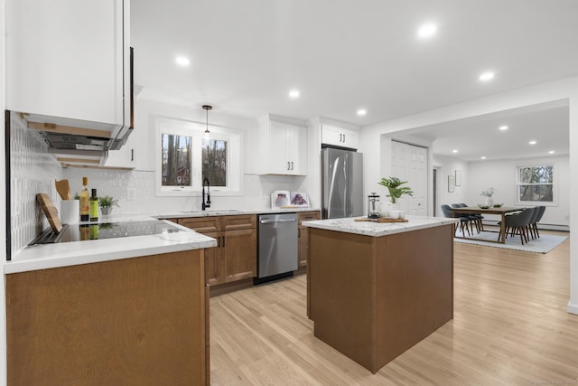 kitchen featuring white cabinetry, stainless steel appliances, a center island, decorative light fixtures, and sink