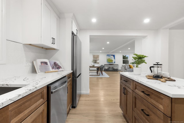 kitchen featuring white cabinets, light wood-type flooring, stainless steel appliances, and light stone countertops