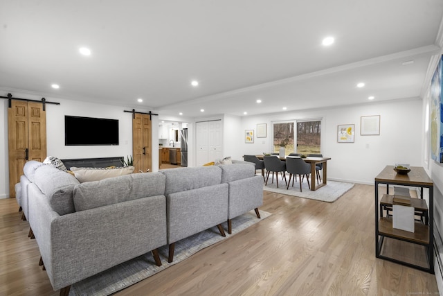 living room with light hardwood / wood-style flooring, a barn door, and ornamental molding