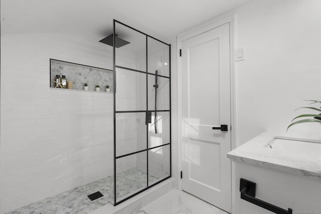 bathroom with vaulted ceiling, a tile shower, and vanity