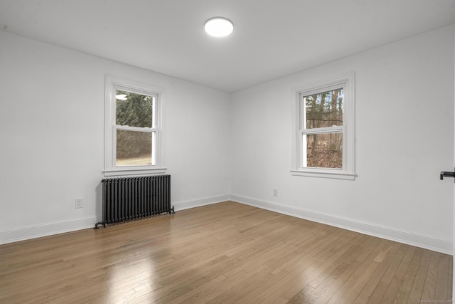 spare room with light wood-type flooring, a wealth of natural light, and radiator