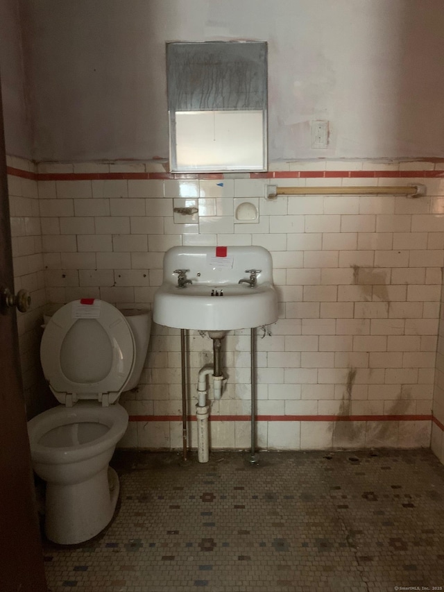 bathroom featuring tile walls, sink, and toilet