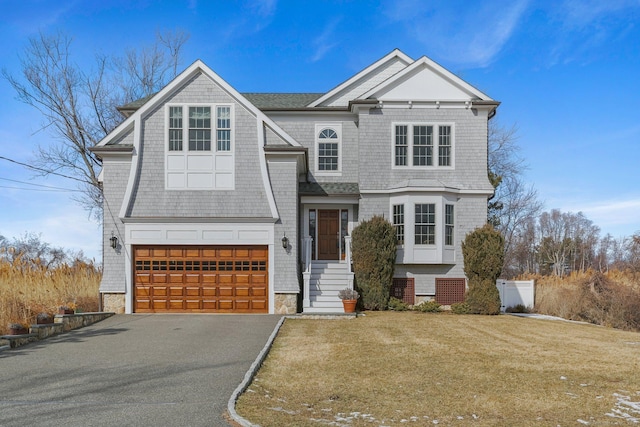 shingle-style home with a garage, driveway, and a front lawn