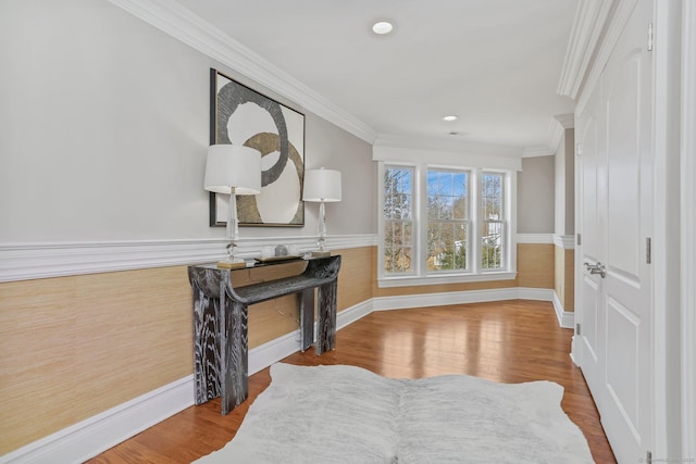 living area with ornamental molding, a wainscoted wall, and wood finished floors